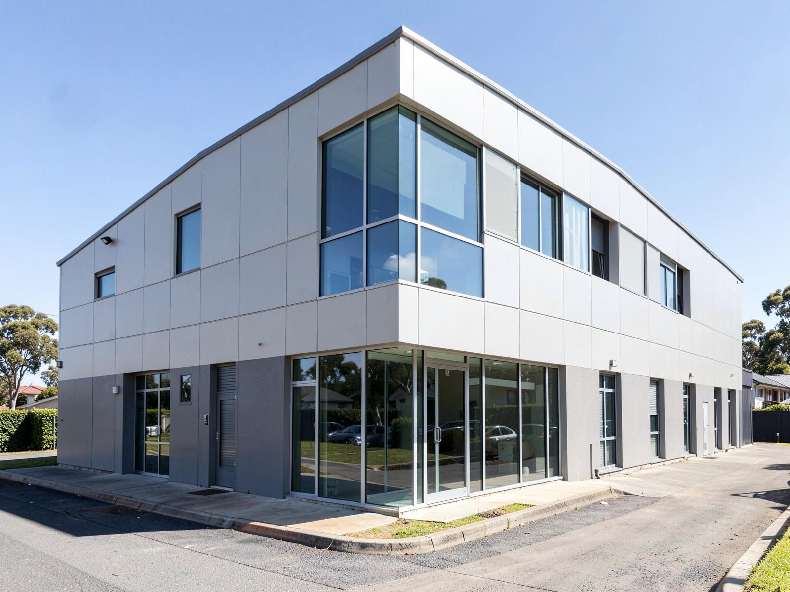 A two-storey suburban office and warehouse building with a glazed corner.