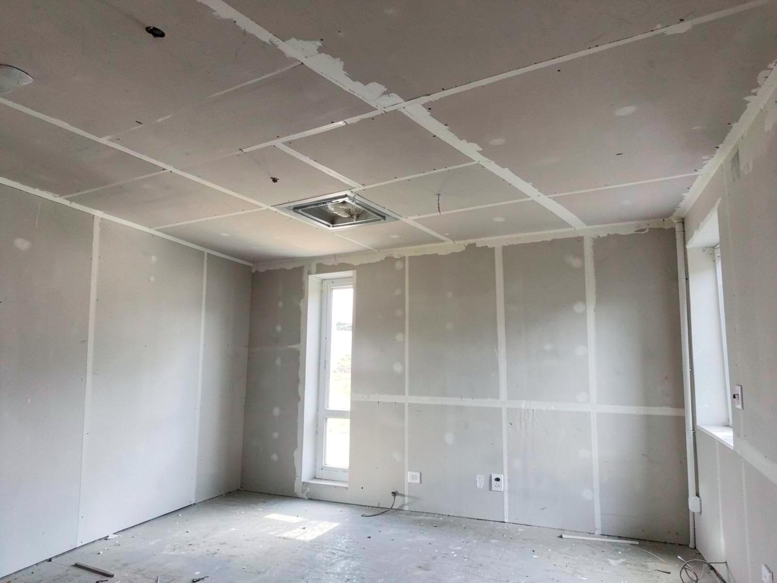 Partly refurbished commercial interior with bare ceiling and new linings.